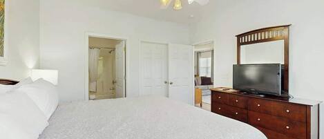 A bedroom with a bed, a dresser, a television, and a ceiling fan.