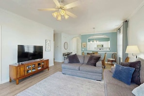 Ein Wohnzimmer mit Fernseher, Sofa und Deckenventilator.