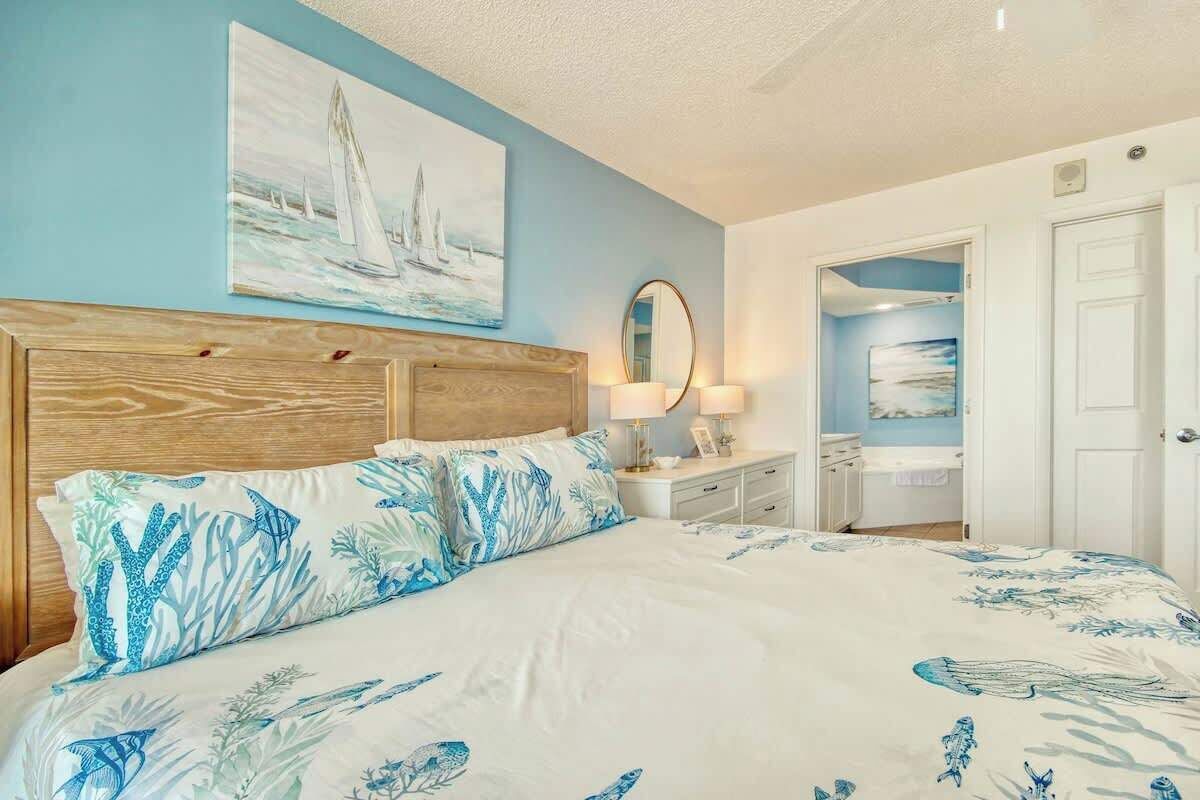 A bedroom with a bed, a nightstand, a mirror, and a painting on the wall.