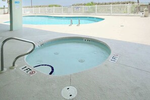 A small hot tub with a 1 FT depth marker, a pool in the background, and a white fence. - East End Escape Retreat (North Myrtle Beach)