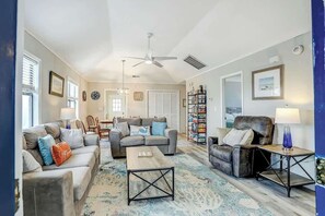 A spacious living room with a ceiling fan, a coffee table, and a bookshelf. - Blue Heron Beach Retreat (North Myrtle Beach)