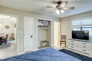 A bedroom with a bed, a ceiling fan, a TV, and a closet with hanging clothes. - Blue Heron Beach Retreat (North Myrtle Beach)