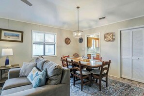 A living room with a sofa, dining table, chairs, and a patterned rug. - Blue Heron Beach Retreat (North Myrtle Beach)