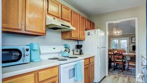 Una cocina con armarios de madera, estufa blanca, microondas y refrigerador.
