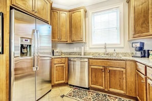 A kitchen with wooden cabinets, stainless steel appliances, and a tiled backsplash. - Twelve Oaks Unit 108-4 (Pawleys Island)
