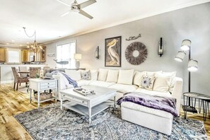 Una sala de estar moderna con un sofá blanco, una mesa de centro y una alfombra estampada.