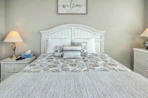 Ein Schlafzimmer mit einem weißen Bett, einem Schild mit der Aufschrift 'welcome to our home' und einer Lampe auf jeder Seite.