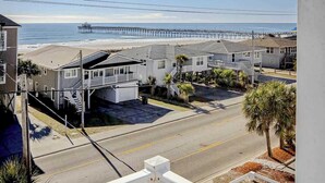 A residential area with houses, a street, and a pier extending into the ocean. - PacMan Get Away Condo (North Myrtle Beach)