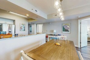 A modern kitchen with a wooden dining table, white cabinets, and artwork on the walls. - Caribbean Resort and Villas 1107 (Myrtle Beach)