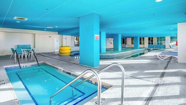 Ein Schwimmbeckenbereich mit mehreren Bahnen, einer Liegefläche mit Stühlen und einem gelben Fitnessball.
