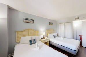 Ein Hotelzimmer mit zwei Betten, einem Nachttisch mit Lampe und einer Tür mit einem roten Gegenstand.