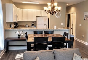 A modern kitchen with white cabinets, a dining table with chairs, and a chandelier. - *1001 World Tour 206 (Myrtle Beach)