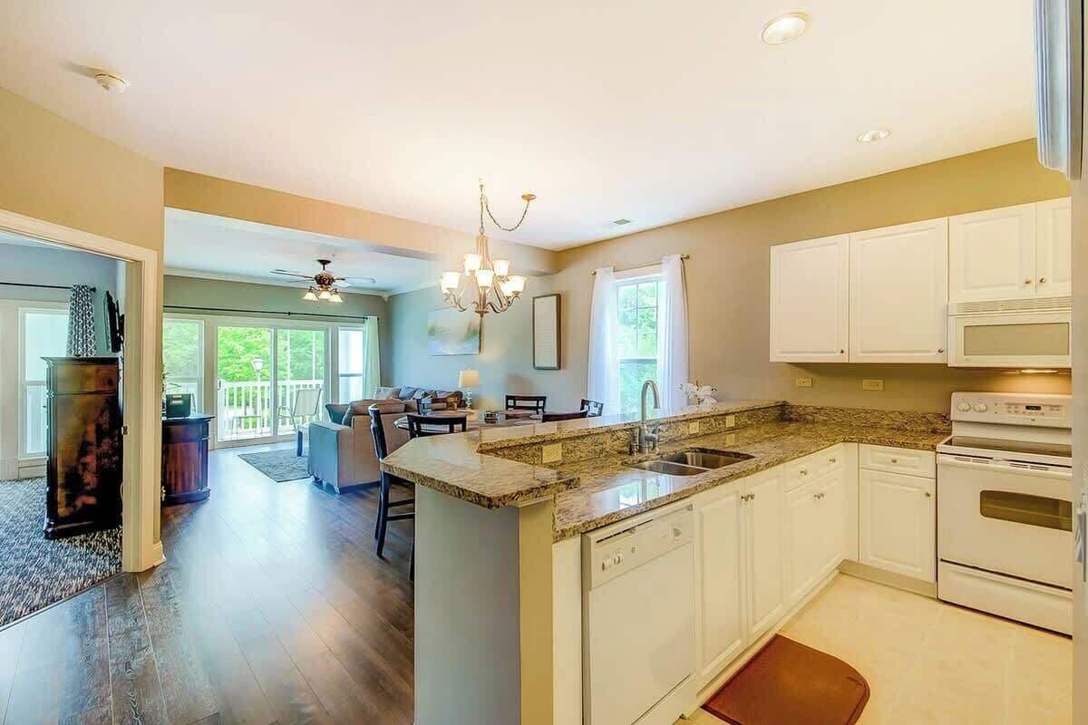 A spacious kitchen with a granite countertop, white cabinetry, and a built-in oven.