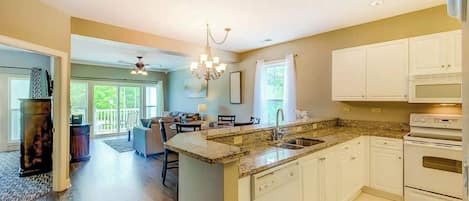 A spacious kitchen with a granite countertop, white cabinetry, and a built-in oven.
