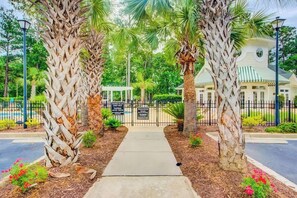 A gated entrance with palm trees, a pathway, and a building with a green roof. - *1001 World Tour 206 (Myrtle Beach)