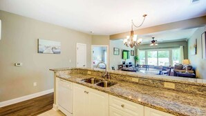 A kitchen with a granite countertop, white cabinets, a double sink, and a chandelier. - *1001 World Tour 206 (Myrtle Beach)