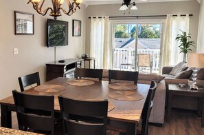 A dining area with a wooden table and chairs, a television mounted on the wall, and a view of the outside through a sliding door. - *1001 World Tour 206 (Myrtle Beach)