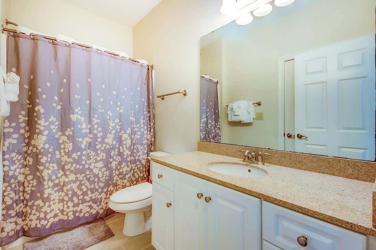 A bathroom with a toilet, sink, and shower curtain.