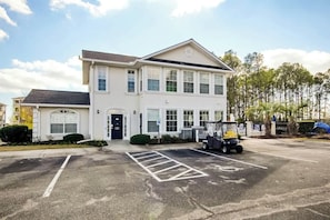A two-story building with a parking lot in front. - Plantation Harbour G-16 (Little River)