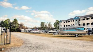 A marina with boats docked, a building with a blue roof, and a gravel road. - Plantation Harbour G-16 (Little River)