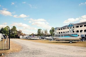 A marina with boats docked, a building with a blue roof, and a gravel road. - Plantation Harbour G-16 (Little River)