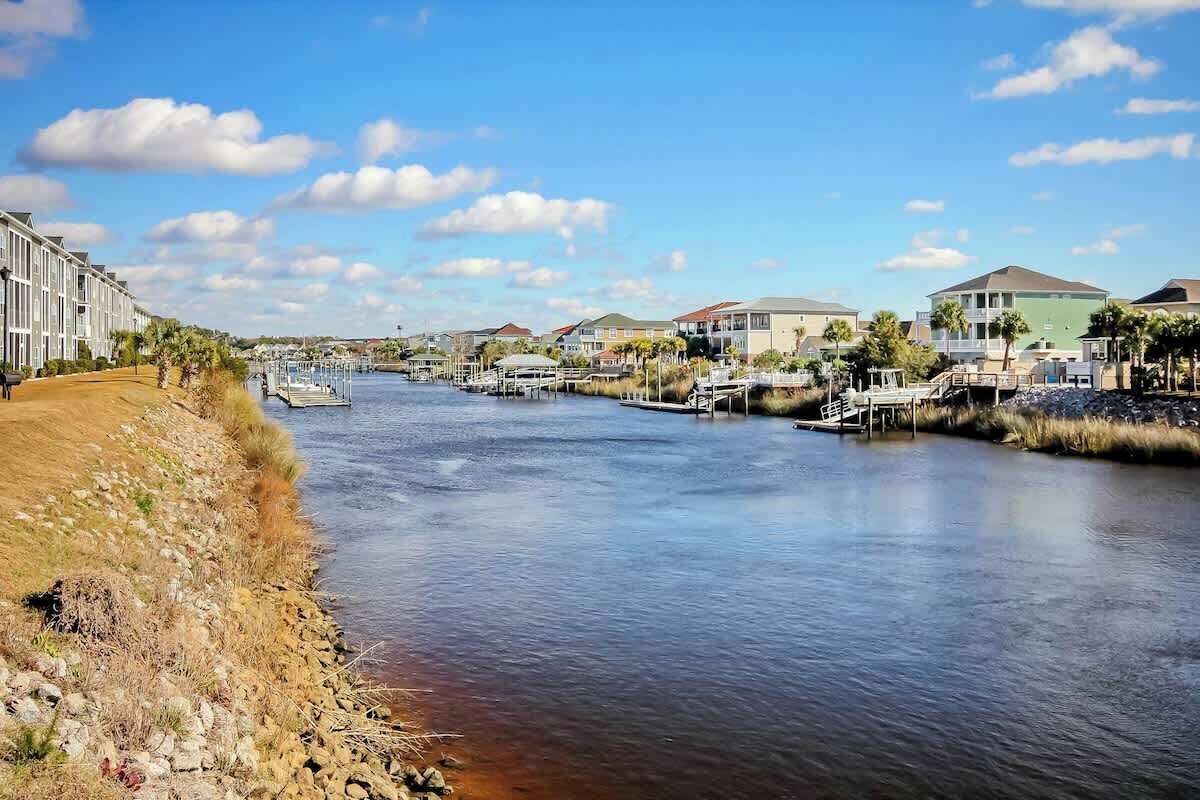 A waterfront property with a marina, docked boats, and a row of houses along the riverbank.