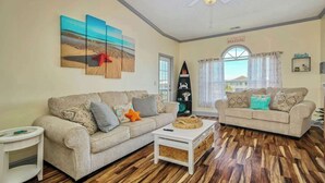 A living room with two sofas, a coffee table, and artwork on the walls. - Plantation Harbour G-16 (Little River)