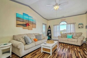 A living room with two sofas, a coffee table, and artwork on the walls. - Plantation Harbour G-16 (Little River)