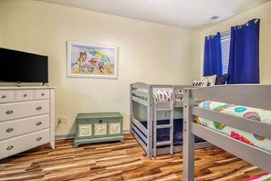 A child's bedroom with bunk beds, a dresser, a television, and a beach-themed painting. - Plantation Harbour G-16 (Little River)