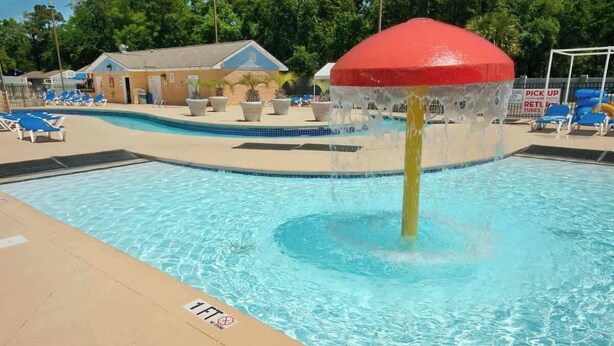 A swimming pool with a water feature, lounge chairs, and a building in the background. - Renaissance Tower 211 (Myrtle Beach)