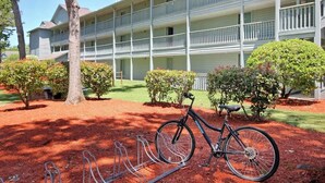 A multi-story building with a balcony on each floor, a bicycle parked in front, and a well-maintained garden with trimmed bushes. - Renaissance Tower 211 (Myrtle Beach)