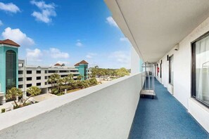 Ein Hotelgang mit blauem Teppich, einem Wägelchen und Blick auf ein Gebäude mit rotem Dach.
