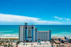 Ein Hochhaus-Hotel mit mehreren Etagen, einem Poolbereich und Blick auf das Meer.