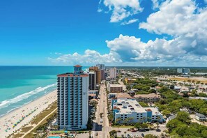 A coastal cityscape with a prominent hotel, beach, and clear skies. - Caribbean Resort 525 (Myrtle Beach)