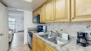 A kitchen with wooden cabinets, a microwave, a coffee maker, and a sink. - Caribbean Resort 525 (Myrtle Beach)