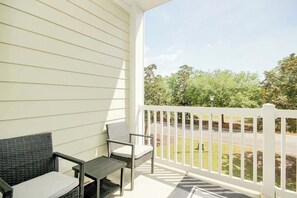 A covered porch with a white railing, a wicker chair, and a small table. - 1017 World Tour Unit 204 (Myrtle Beach)