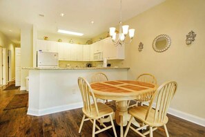 A kitchen with white cabinets, a central island, and a dining area with wooden chairs. - 1017 World Tour Unit 204 (Myrtle Beach)