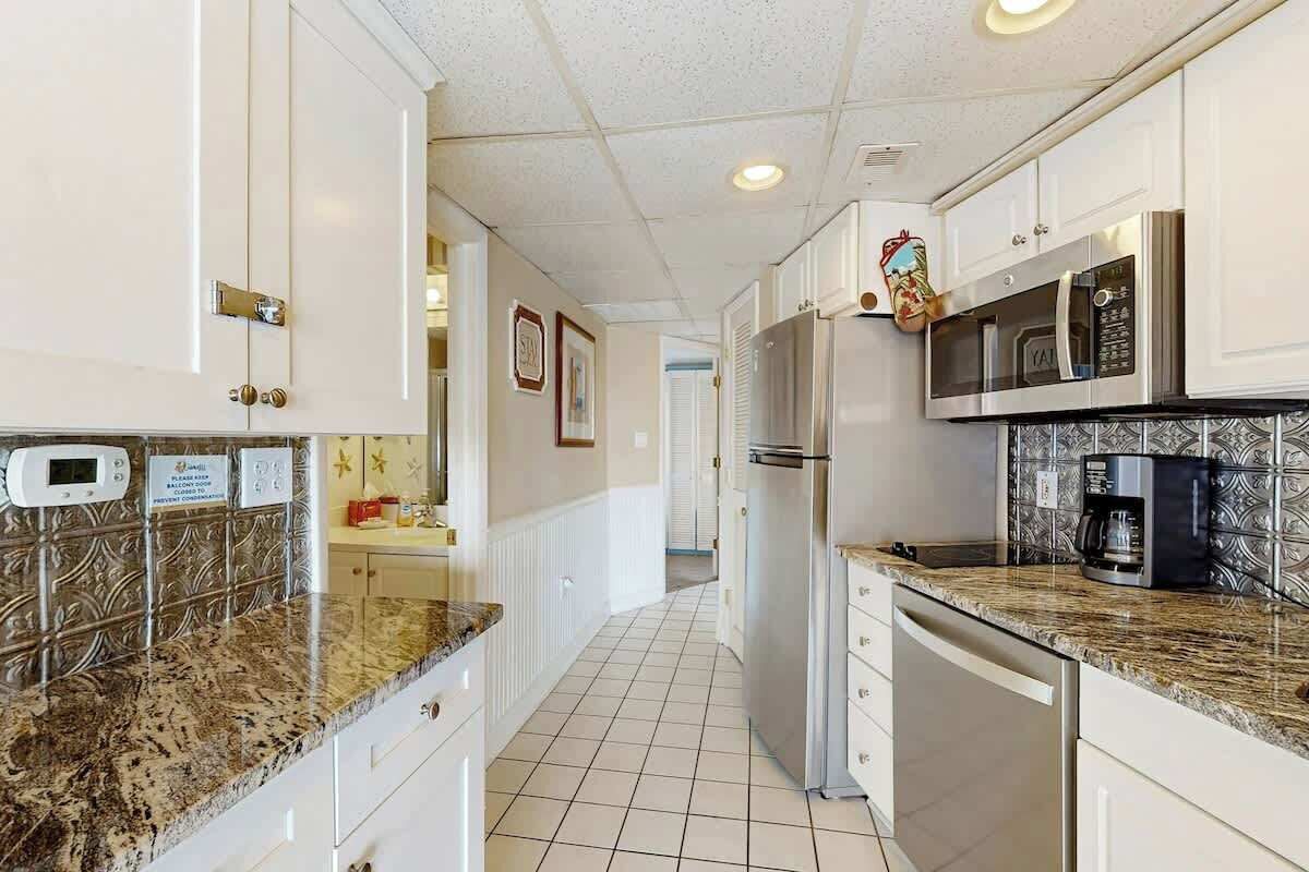 A kitchen with white cabinets, a stainless steel refrigerator, a microwave, and a coffee maker.