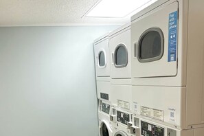 A row of white, stacked laundry machines with a 'Pay with your phone' sign. - St Clement's Unit 409 (Myrtle Beach)