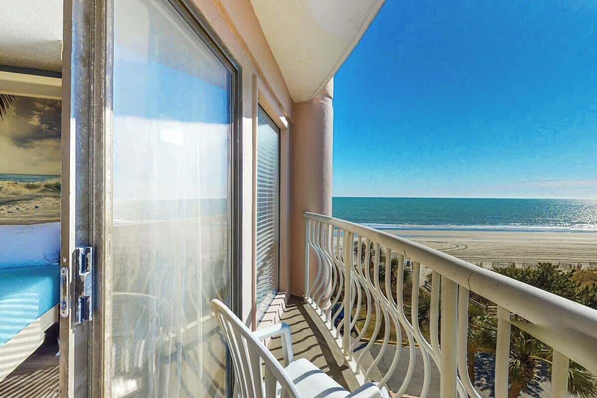 A balcony with a view of the beach and ocean.