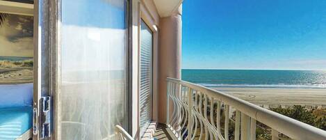 A balcony with a view of the beach and ocean.