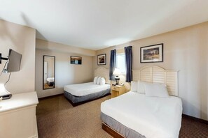 A hotel room with two beds, a desk, a mirror, and a window with curtains. - Harbourgate Unit 132 (North Myrtle Beach)