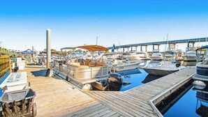 Un puerto deportivo con barcos amarrados, un muelle de madera y un cielo azul despejado.