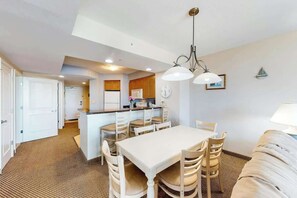 A compact kitchen with a central island, dining area with chairs, and a sofa. - Harbourgate Unit 132 (North Myrtle Beach)