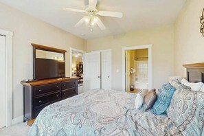 Ein Schlafzimmer mit Bett, Kommode, Spiegel und Deckenventilator.