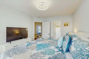 A bedroom with a bed, a television, and a door leading to another room. - The Tickled Pink Retreat (Murrells Inlet)