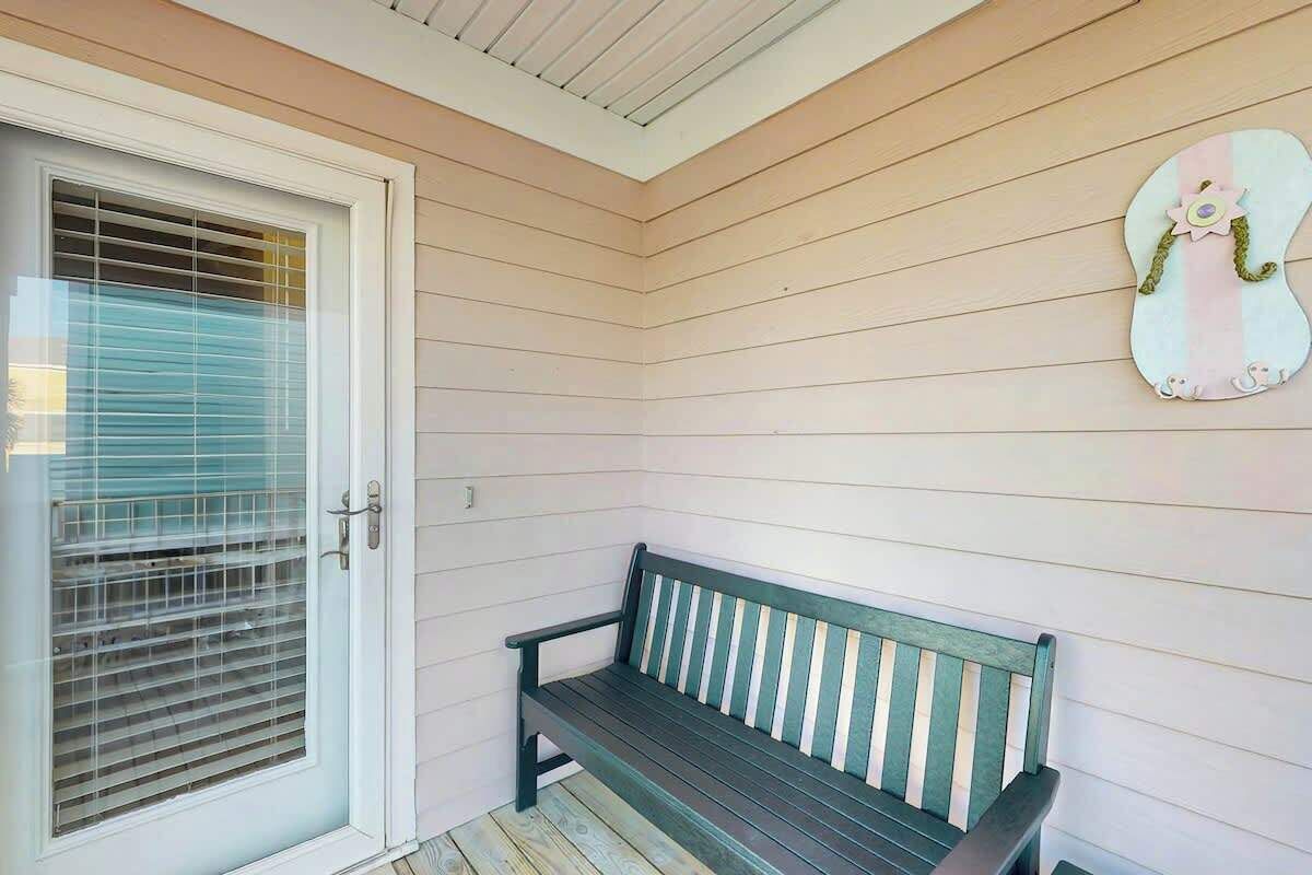 A wooden bench with a white door and blinds in the background.
