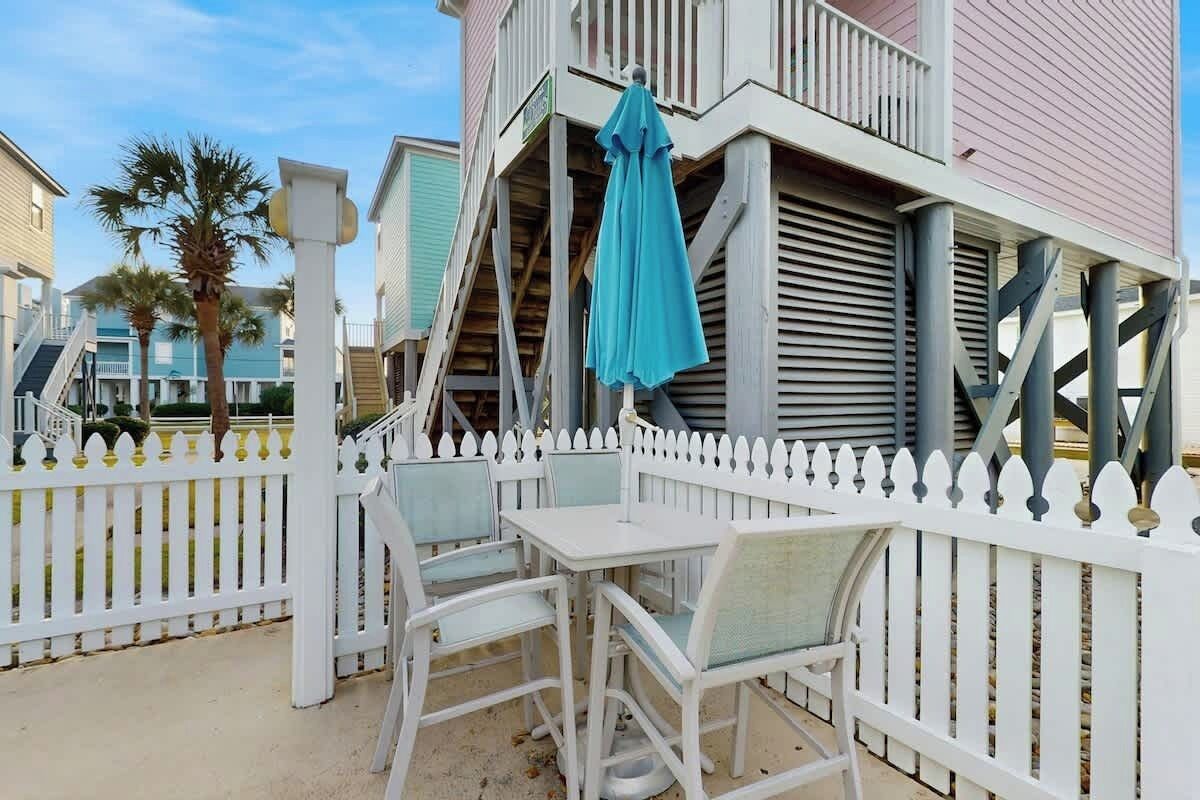 A balcony with white railings and a table with chairs.