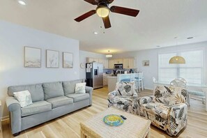 Ein Wohnzimmer mit Sofa, Sesseln, Couchtisch und Deckenventilator.