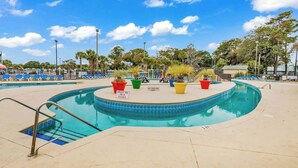 A swimming pool with a circular edge, surrounded by lounge chairs and potted plants. - Myrtle Beach Resort B-229 (Myrtle Beach)